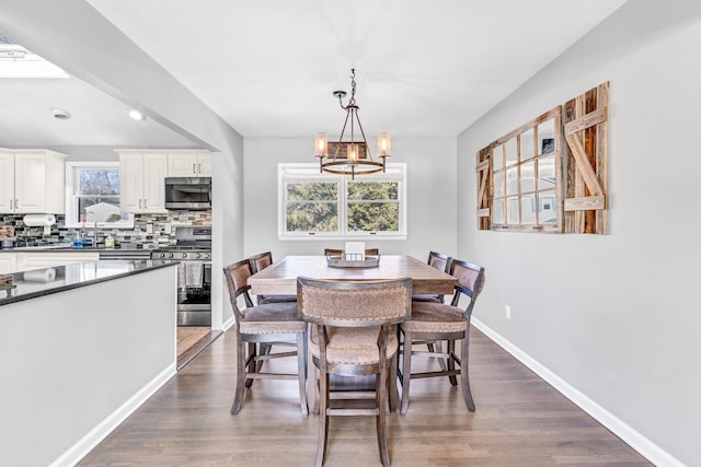 dining space with dark wood-style floors, baseboards, and an inviting chandelier