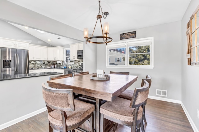 dining area featuring baseboards, visible vents, dark wood finished floors, vaulted ceiling, and a chandelier