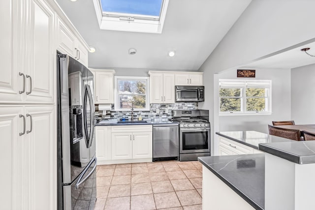 kitchen with appliances with stainless steel finishes, dark countertops, and white cabinetry