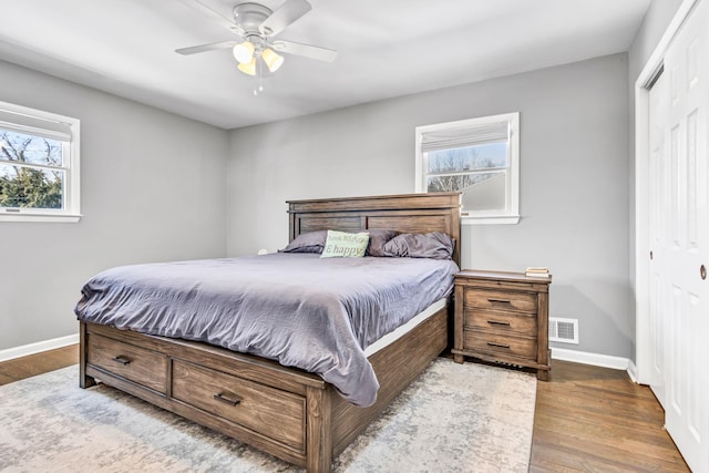 bedroom featuring a closet, visible vents, baseboards, and wood finished floors