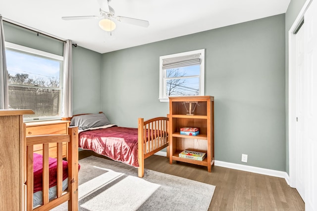 bedroom with dark wood-style flooring, a closet, a ceiling fan, and baseboards