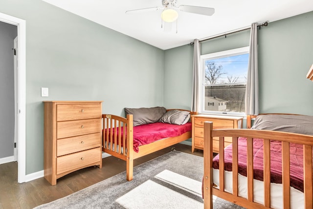 bedroom with ceiling fan, baseboards, and dark wood-type flooring