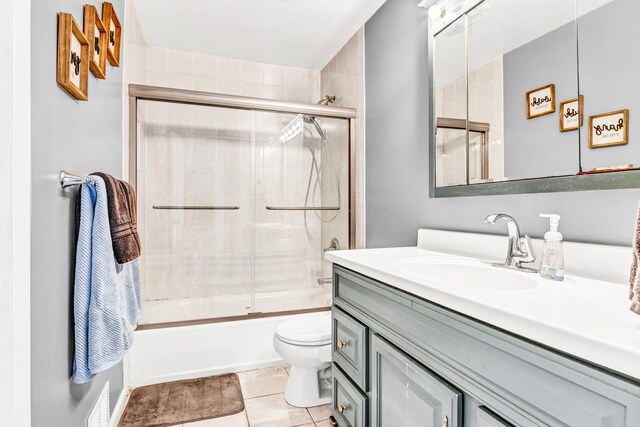 bathroom featuring enclosed tub / shower combo, vanity, tile patterned flooring, and toilet