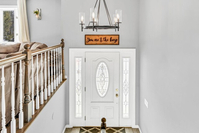 entryway featuring plenty of natural light, baseboards, and an inviting chandelier