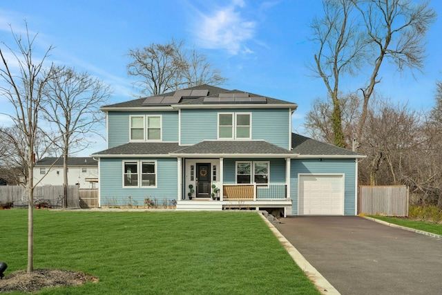 view of front of property featuring solar panels, a porch, fence, a garage, and a front lawn