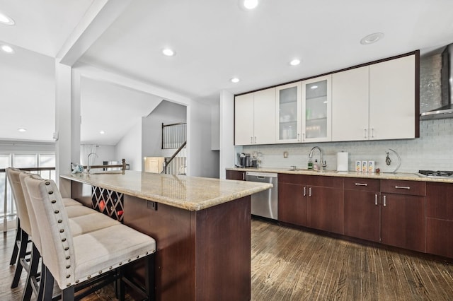 kitchen featuring light stone countertops, a kitchen bar, glass insert cabinets, and stainless steel dishwasher