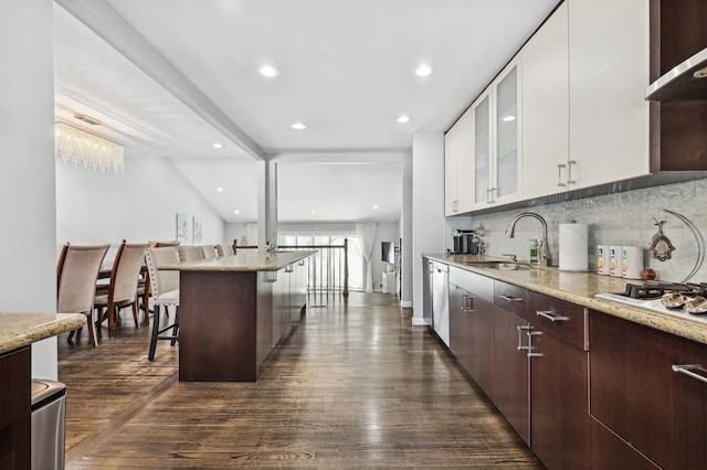 kitchen featuring glass insert cabinets, a breakfast bar area, dark brown cabinets, white cabinetry, and a sink