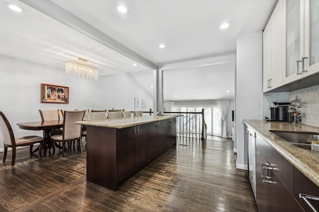 kitchen featuring dark brown cabinetry, a kitchen bar, white cabinetry, and dark wood finished floors