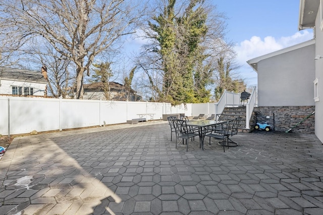 view of patio with a fenced backyard, stairway, and outdoor dining area