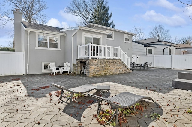 back of property featuring a patio area, a chimney, fence, and stucco siding