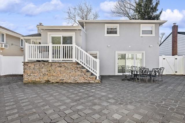 back of house featuring a patio area, a gate, fence, and stucco siding