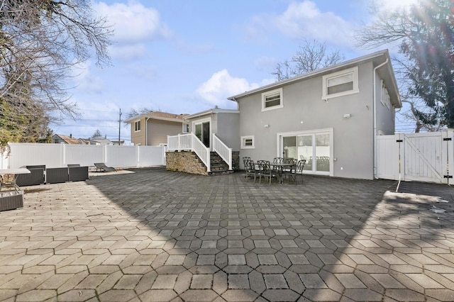 rear view of property with a patio, fence, an outdoor living space, a gate, and stucco siding