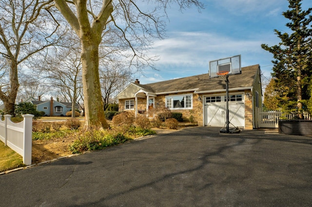 view of front of property with a garage, fence, stone siding, driveway, and a gate