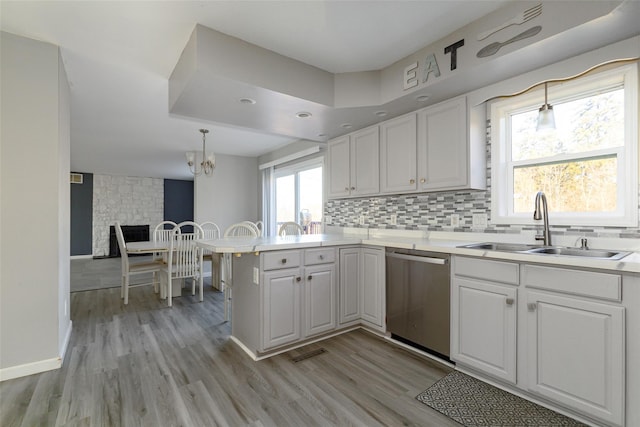 125 Cedar Hill Rd, Wappingers Falls, NY 12590 - kitchen featuring stainless steel dishwasher, a sink, a peninsula, light wood-style flooring, and a chandelier