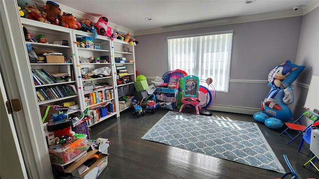 recreation room featuring a baseboard heating unit, dark wood finished floors, and crown molding