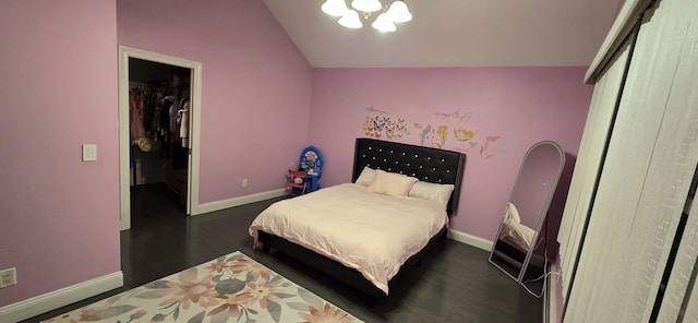 bedroom with baseboards, dark wood-type flooring, a spacious closet, vaulted ceiling, and a closet