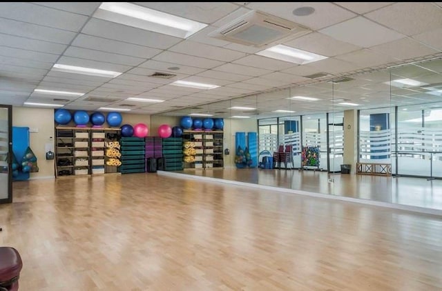 exercise room with hardwood / wood-style flooring and a paneled ceiling