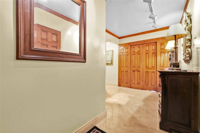 corridor with track lighting, marble finish floor, crown molding, and baseboards