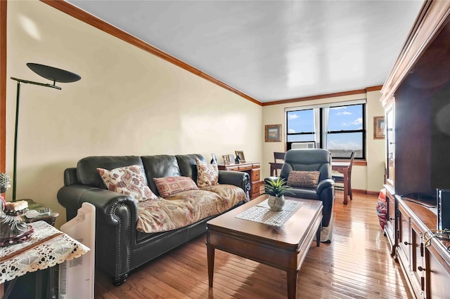 living room with ornamental molding, wood-type flooring, and baseboards