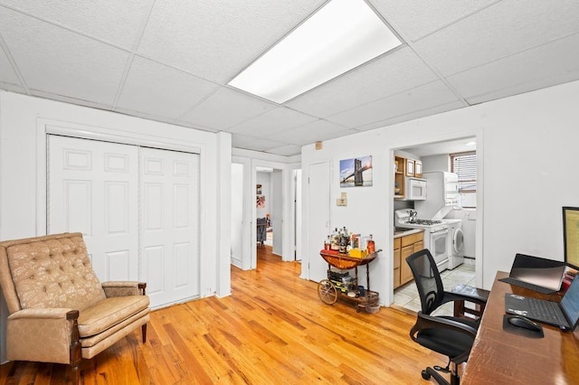 home office with light wood-type flooring, washer / clothes dryer, and a drop ceiling