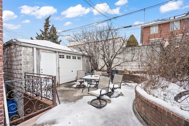 snow covered patio with an outdoor structure and a garage