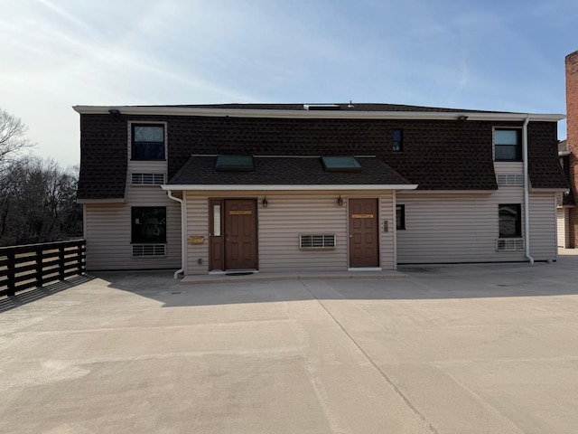 view of front of property featuring a patio area, a shingled roof, a chimney, and fence