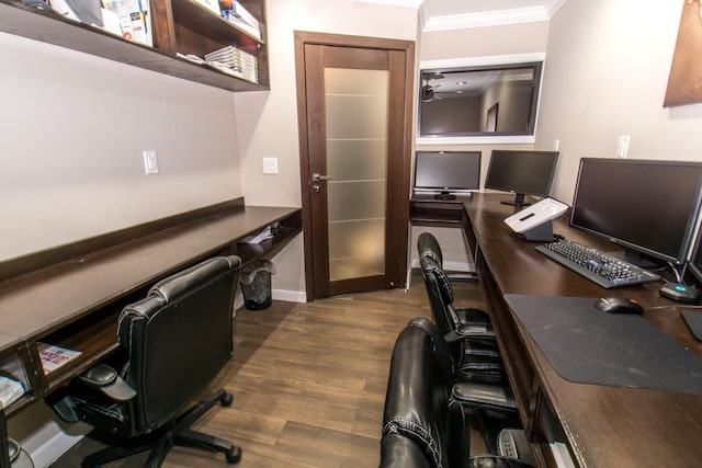 home office featuring ceiling fan, built in desk, dark hardwood / wood-style flooring, and ornamental molding