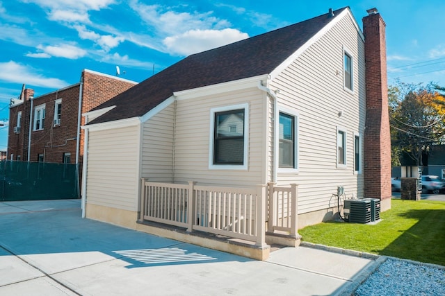 view of side of property featuring central air condition unit and a yard