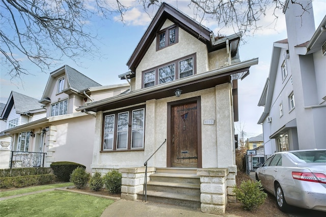 english style home featuring stucco siding and a front yard