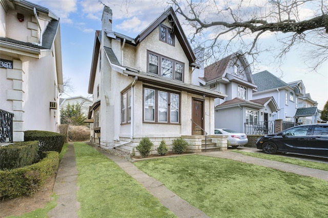 view of front of property featuring a residential view, stucco siding, a front yard, and a chimney