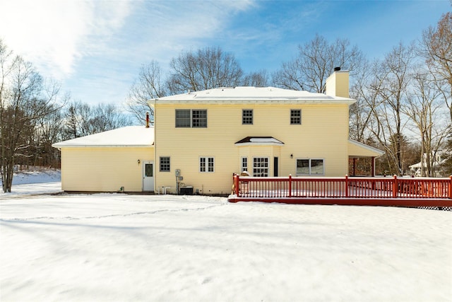 snow covered property with a chimney and a wooden deck