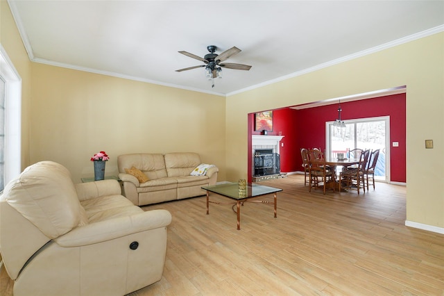 living room featuring ornamental molding, ceiling fan, a tile fireplace, wood finished floors, and baseboards