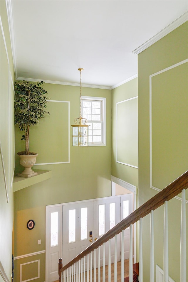 staircase featuring a high ceiling, crown molding, and a chandelier