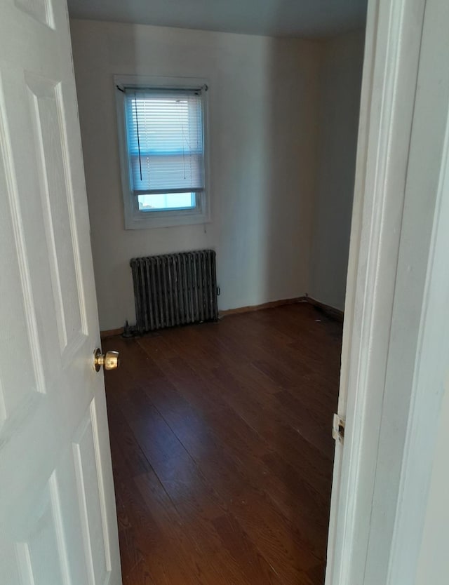 spare room with dark wood-type flooring and radiator