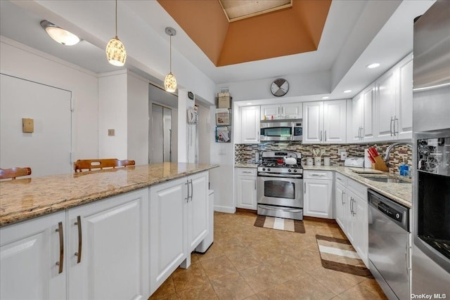 kitchen with decorative backsplash, stainless steel appliances, white cabinetry, pendant lighting, and a sink