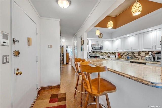 kitchen with light stone counters, stainless steel appliances, white cabinets, hanging light fixtures, and backsplash