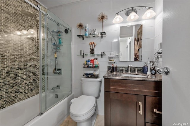 bathroom with toilet, combined bath / shower with glass door, tile walls, and vanity