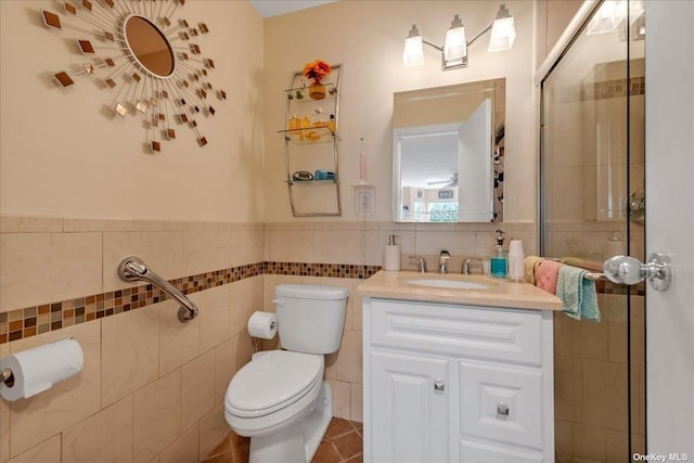 full bathroom featuring a wainscoted wall, tile walls, toilet, a shower with shower door, and vanity