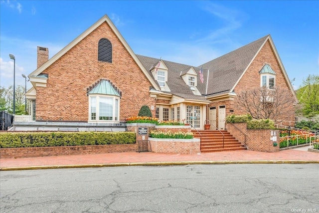 view of front facade with brick siding, fence, and a chimney