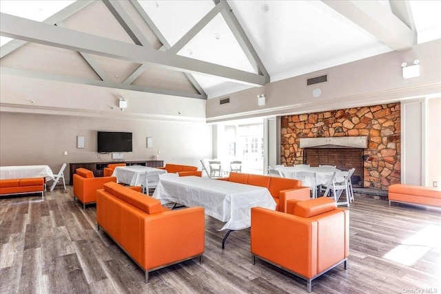 living room featuring visible vents, wood finished floors, beamed ceiling, a fireplace, and high vaulted ceiling