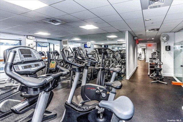 gym with a paneled ceiling, baseboards, and visible vents