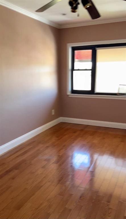 spare room featuring ceiling fan, baseboards, wood finished floors, and ornamental molding