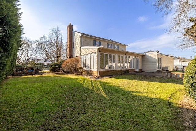 back of house with a sunroom, a lawn, and a chimney