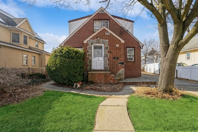 view of front of home with a front yard, brick siding, and fence