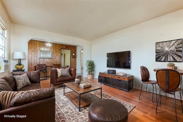 living area with arched walkways and wood finished floors