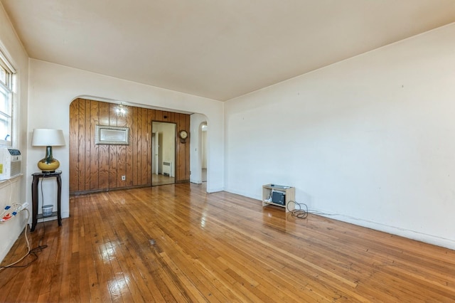 spare room with arched walkways, wood-type flooring, and baseboards