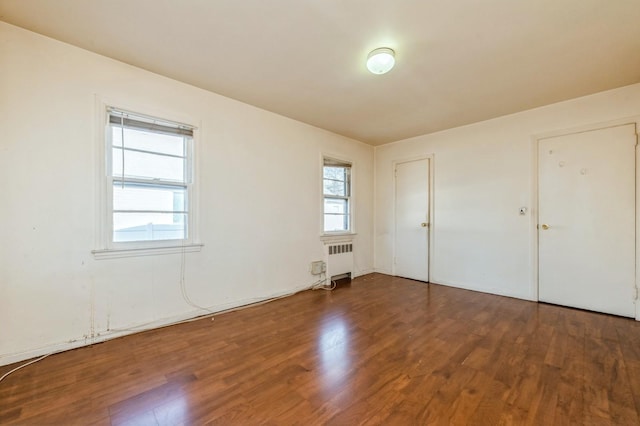 empty room with radiator heating unit and wood finished floors