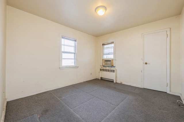 unfurnished room with cooling unit, radiator, and dark carpet