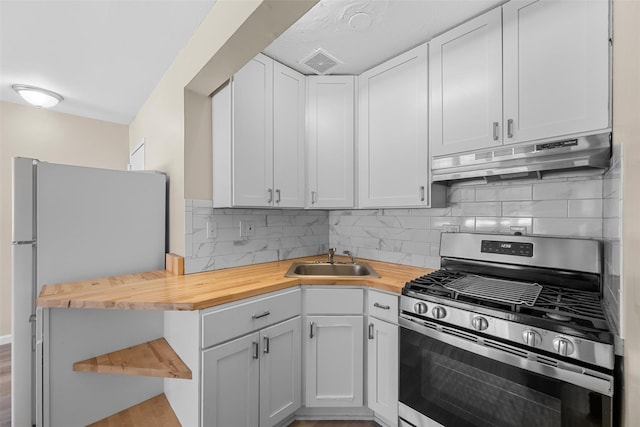 kitchen with wooden counters, appliances with stainless steel finishes, white cabinetry, and under cabinet range hood