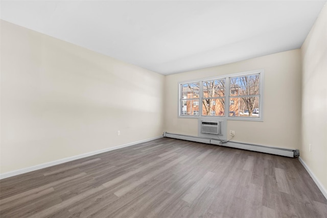 empty room featuring a wall unit AC, light wood-style flooring, baseboards, and baseboard heating